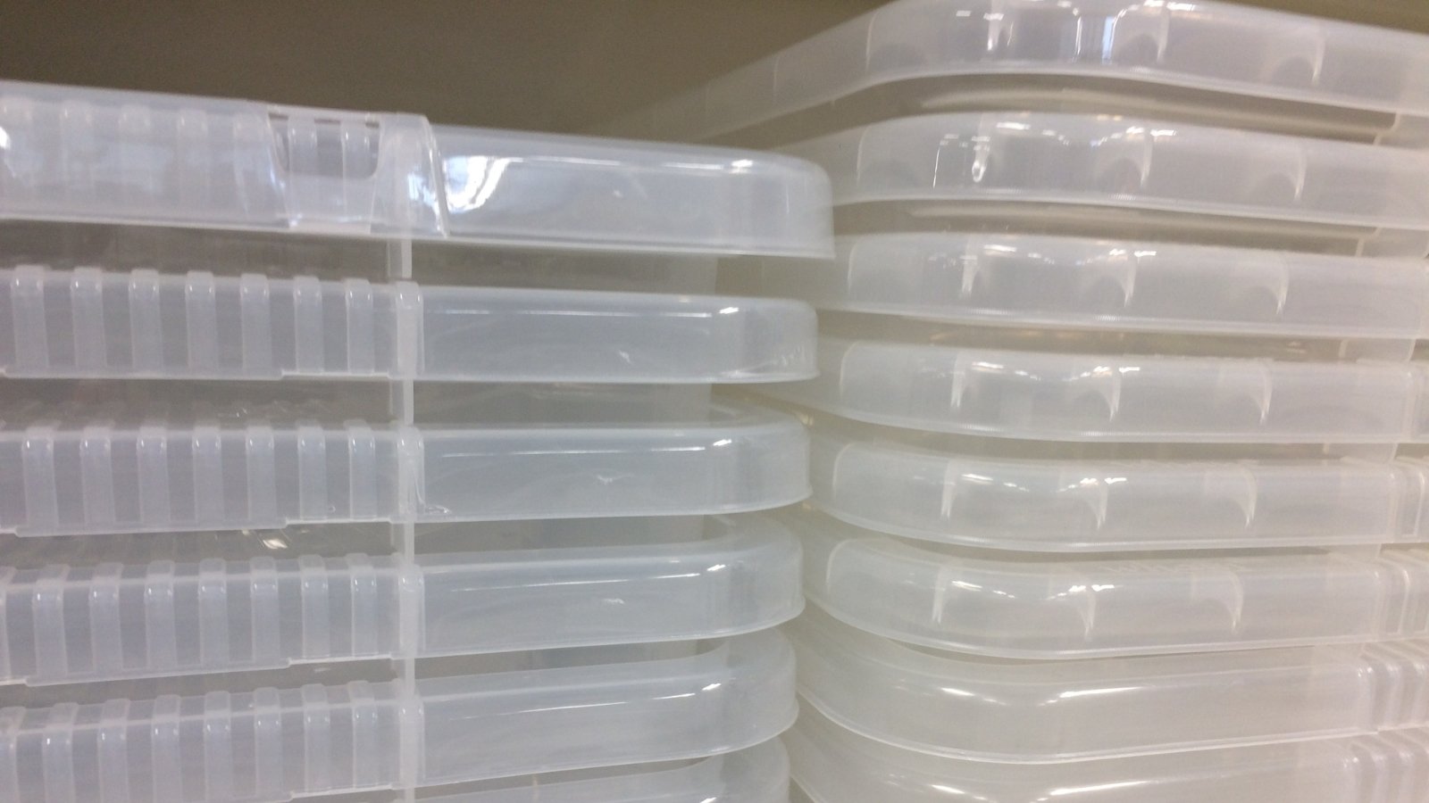 A stack of translucent plastic containers with lids, organized for use in cultivation or storage purposes.